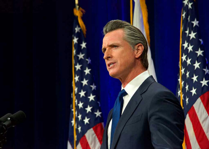 Man speaking at podium with American flags behind him.
