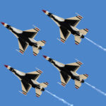 Four military jets flying in formation against a clear blue sky