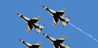 Four military jets flying in formation against a clear blue sky