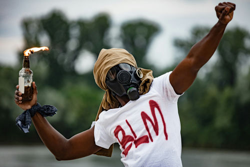 shutterstock1760658014jpg Person in gas mask with Molotov cocktail, BLM shirt.