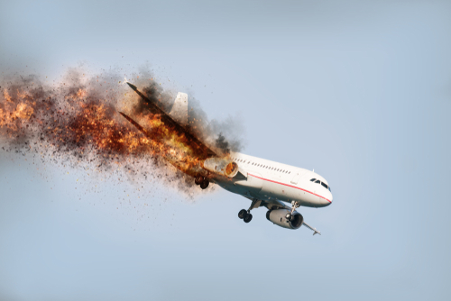 An airplane experiencing an explosion mid-flight with smoke and fire trailing behind