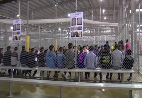 Abstract,,Blur,,Bokeh,Background,,Defocusing,-,Image,For,The,Background. A group of young individuals seated in a detention center surrounded by security fencing and informational posters