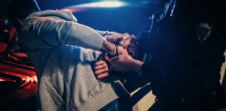 Person being handcuffed by police officer at night.