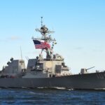 naval destroyer with flags sailing on open water