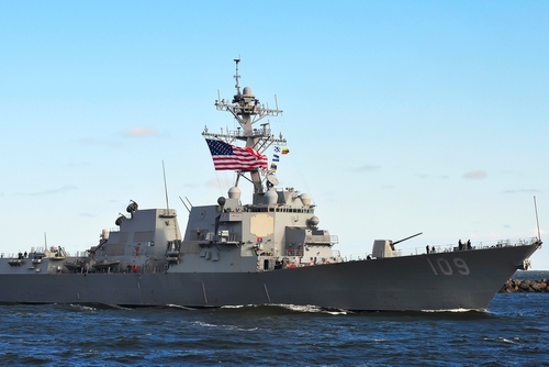 naval destroyer with flags sailing on open water