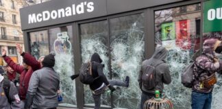 Protesters vandalizing a McDonald's restaurant with broken windows