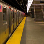 Subway station platform with train and exit stairs.