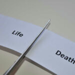 Scissors cutting paper labeled Life and Death