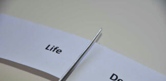 Scissors cutting paper labeled Life and Death