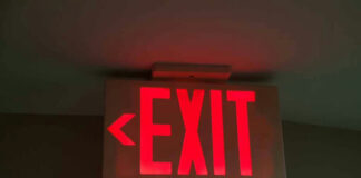 Red illuminated exit sign with left arrow.
