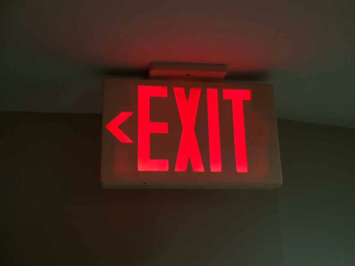 Red illuminated exit sign with left arrow.