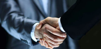 Two individuals in suits shaking hands firmly.