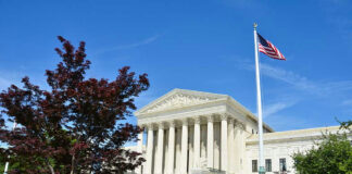 Supreme Court building with American flag and trees.