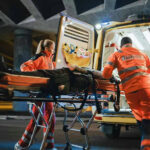 Paramedics loading patient into ambulance at night.