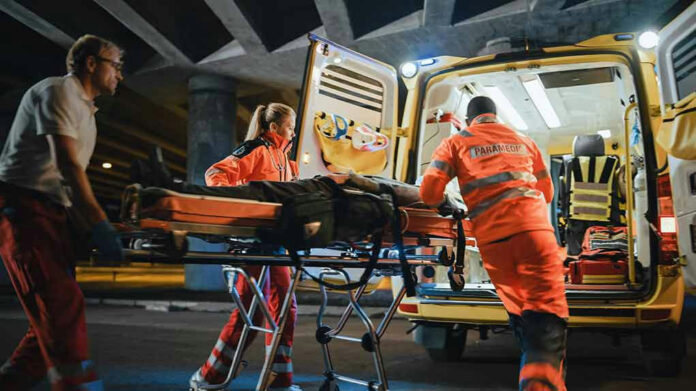 1878018001-1 Paramedics loading patient into ambulance at night.