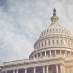 Missing Records Spark New Capitol Controversy US Capitol dome with American flag and cloudy sky.