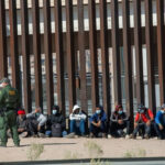 High Court Clears Path For Haiti Deportations Border patrol agent with group of seated immigrants.