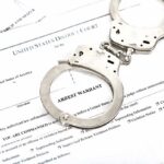 Handcuffs on an arrest warrant document