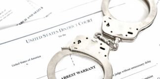 Handcuffs on an arrest warrant document
