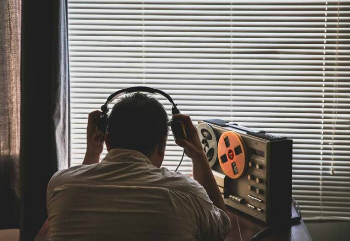 shutterstock_1478666012-5- Person wearing headphones listening to a reel-to-reel tape recorder