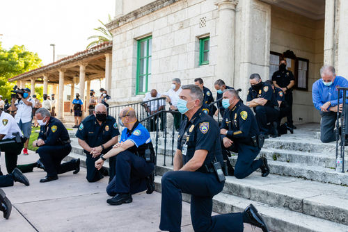 Police officers kneeling on steps, some wearing face masks.
