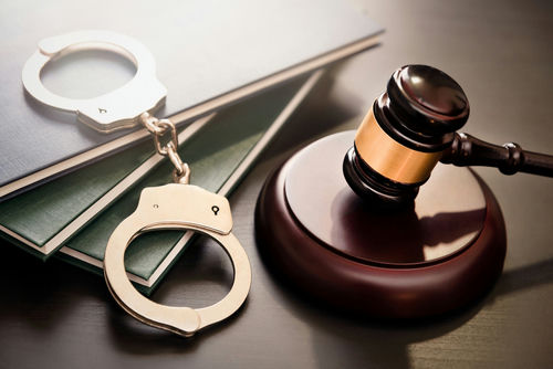 shutterstock_1917987797 Gavel, handcuffs, and legal books on a dark surface.