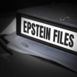 Who Is Still Being Protected In Epstein Files? A black binder labeled 'EPSTEIN FILES' with papers and office supplies nearby