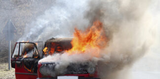 A car engulfed in flames with smoke billowing out