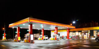 A gas station illuminated at night with fuel pumps and a convenience store