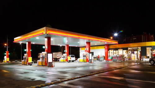 A gas station illuminated at night with fuel pumps and a convenience store