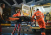 Paramedics loading patient into ambulance at night.