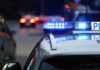 Find My MacBook Beat The System Police car with flashing blue lights on street.