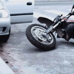 Gunfire Over Motorcycle—One Minute, One Death Motorcycle lying on the street beside a car with an open door