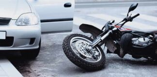 Motorcycle lying on the street beside a car with an open door