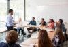 Huge Settlement, Honors Intact? Teacher speaking to students in a classroom discussion