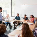 Huge Settlement, Honors Intact? Teacher speaking to students in a classroom discussion