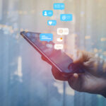 A hand holding a smartphone with social media notifications displayed above it