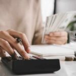 Stop Starving—Build Income, Not Guilt person using calculator while holding cash