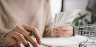 person using calculator while holding cash