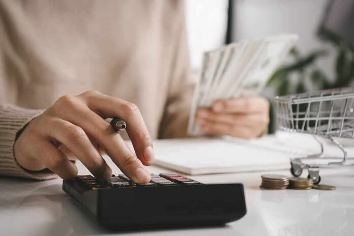 person using calculator while holding cash