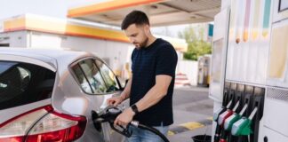 Man fueling a silver car at a gas station