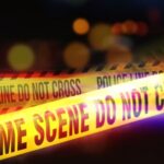 Open Borders, Brutal Consequences? Yellow police tape marking a crime scene with blurred lights in the background