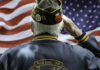 Veteran saluting in front of American flag.