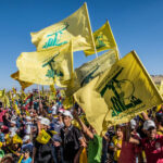 Crowd Roars Loyalty — Tehran’s Grip Shows People waving Hezbollah flags at a large outdoor gathering.