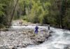 Rescue workers in helmets standing along a fast-flowing forest river