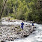 Popular Spot, Zero Safeguards—Why? Rescue workers in helmets standing along a fast-flowing forest river