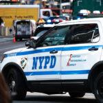 Manhattan Worship Turns Violent — Why? NYPD police car on a city street scene.