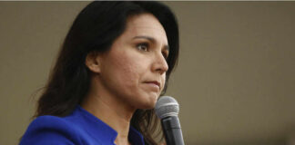 Woman in blue blazer holding a microphone.