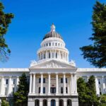 Tax Hike Backfires—Leader Toppled In Scandal State capitol building with white dome and columns framed by trees