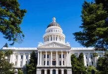State capitol building with white dome and columns framed by trees